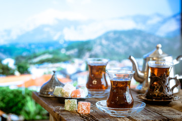 Glass Cup of turkish tea served in traditional style with summer outdore view