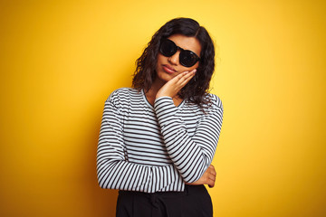 Transsexual transgender woman wearing sunglasses over isolated yellow background thinking looking tired and bored with depression problems with crossed arms.