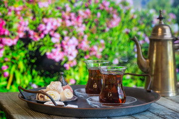 Glass Cup of turkish tea served in traditional style with summer outdore view