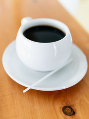 Tada with coffee, white color in small plate on the table.