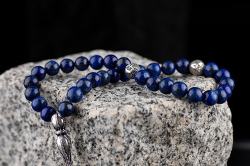 Prayer beads on black background. Close-up Rosary on granite stone