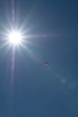Person With Open Parachute In The Middle Of The Sky With Bright Sun 
