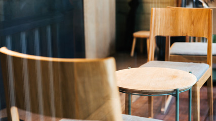 Close-up wooden chairs and empty low table inside cafe. Warm and cozy atmosphere.