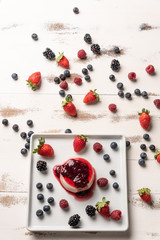 Delicious italian dessert panna cotta with berry sauce, fresh berries on white wooden background