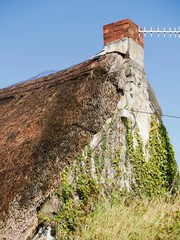 Old thatched rood of a small house in Ireland, blue cloudy sky, Rural environment.