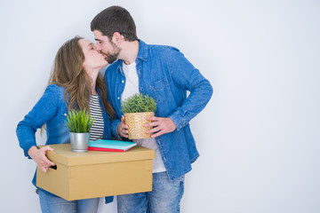 Young beautiful couple holding cardboard boxes very happy for moving to a new home over white isolated background