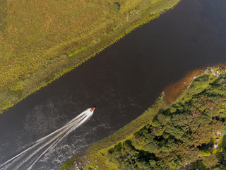 Aerial top view on a boat moving in a river.