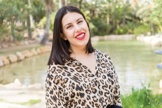 Young beautiful woman with red lips smiling happy at garden