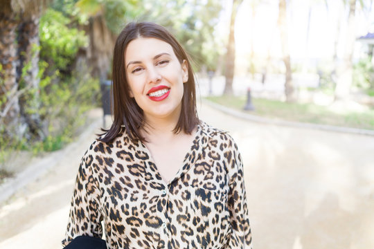Young beautiful woman with red lips smiling happy at garden