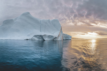 Arctic nature landscape with icebergs in Greenland icefjord with midnight sun sunset sunrise in the...