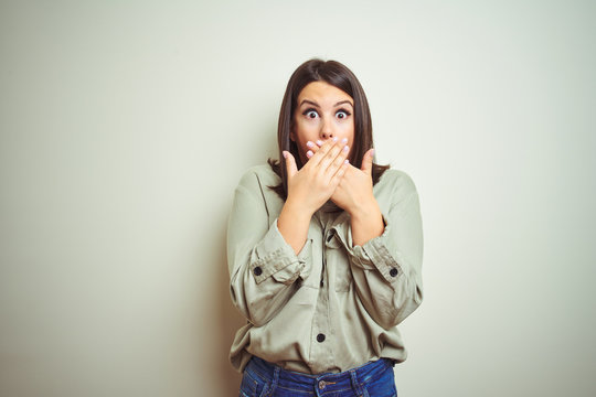 Young beautiful brunette woman wearing green shirt over isolated background shocked covering mouth with hands for mistake. Secret concept.