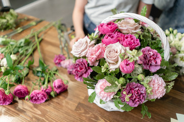 Woman florist create flower arrangement in a wicker basket. Beautiful bouquet of mixed flowers. Floral shop concept . Handsome fresh bouquet. Flowers delivery