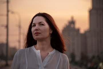 Portrait of a middle-aged woman in profile in a white blouse . Against the background of the city.