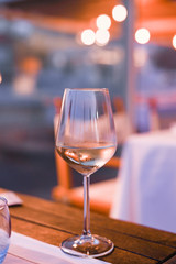 A glass of white wine on a table in a restaurant. Toned photo. Glare and light spots. Free space for text