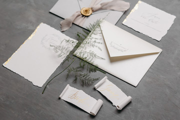Wedding details flat lay. Wedding invitation and scroll paper. Bottle with fragrance. Ring box. Simple bouquet.