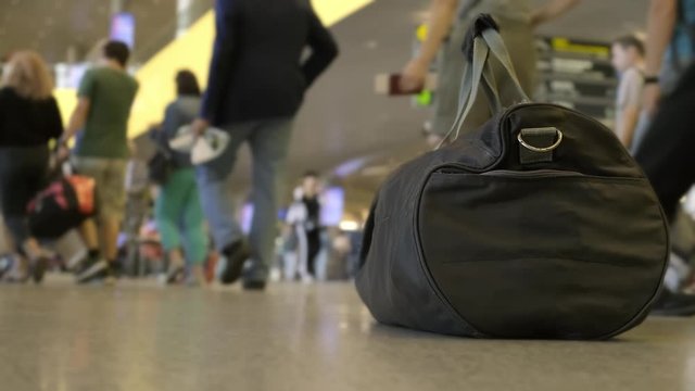 bag of explosives left by terrorist at the airport. Blurred background. sports bag on floor at the airport on the background of walking crowd of passengers.
