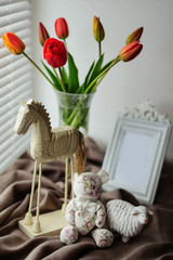 Statuette of wooden horse with bear and tulips in home decor 