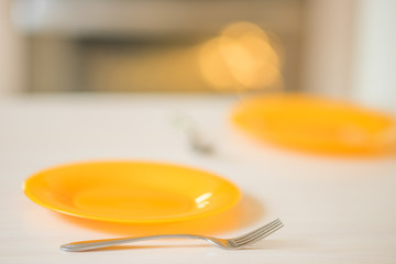 table with orange plates and forks, preparation for the food process.