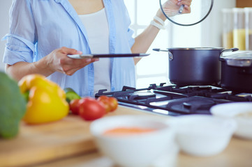 Young woman standing by the stove in the kitchen