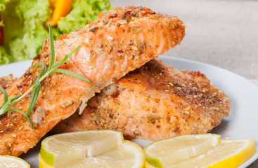 Grilled salmon with spices, lemon and basil, on a light plate.