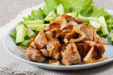 Roasted meat with onions and spices on an old wooden background. Ukrainian national food.