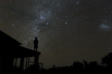 alone woman on rooftop watching mliky way and stars in the night sky on Bali island.