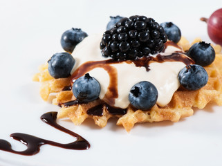 Sweet waffles with sour cream and fruit on a light background.