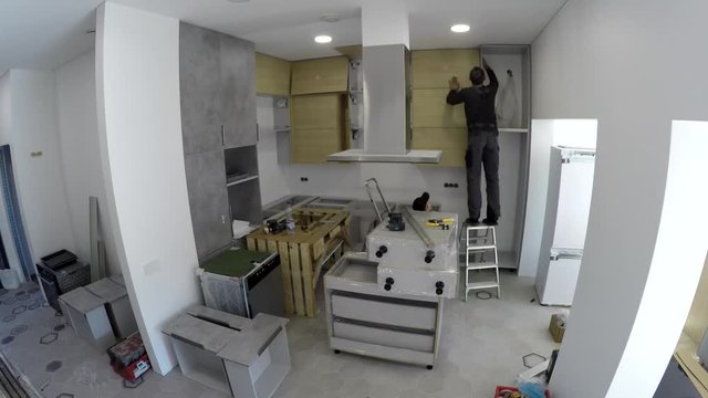 Skilled workers installing kitchen furniture and home appliances. Timelapse