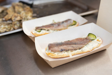 The counter on which lies a fish sandwich in an eco-friendly paper plate. Food and cooking equipment at a street food festival