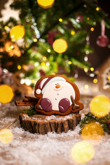 Fototapeta na wymiar Holiday traditional food bakery. Gingerbread happy sitting Snowman or snowball in cozy warm decoration with garland lights