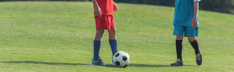 Obraz premium panoramic shot of boys playing football on grass