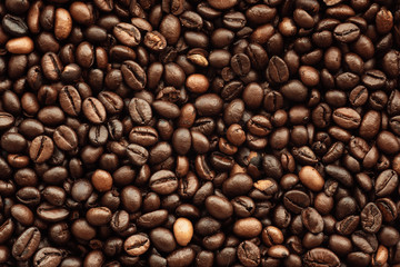 Fresh roasted brown coffee beans, top view of seeds texture as food background for design, macro photo