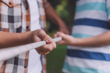 cropped view of multicultural boys competing in tug of war