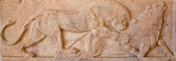 Ancient bas-relief with a scene with lion attacking a bull