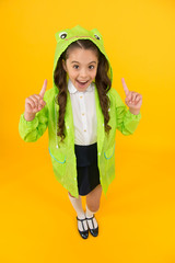 Fototapeta na wymiar Fashion trends in case of rain. Happy child got idea with fashion look on yellow background. Small girl with long hair smiling in fashion rain poncho. Fashion waterproof raincoat for little kid