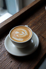 Taza de café con leche sobre una mesa de madera rústica en una cafeteria