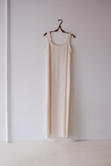Simple wedding dress and hanger on white wall.