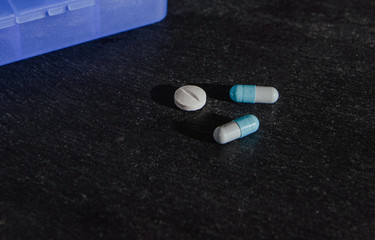 Medications, tablets are on a dark, black countertop. Medical and pharmaceutical concept. Help in taking medicine, regularity. Drug abuse.