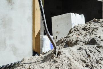 A shovel driven into built-up sand. The concept of building, building a house, apartment. Equipment when building your own home. Renovation, improving the comfort of living in the apartment.