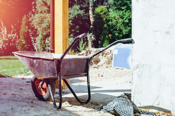 Wheelbarrow in front of the construction site. The concept of building, building a house, apartment. Equipment when building your own home. Renovation, improving the comfort of living in the apartment