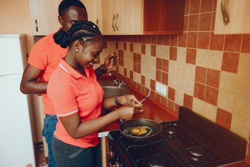 a beautiful young black girl in a pink T-shirt and blue jeans standing at home in the kitchen with...
