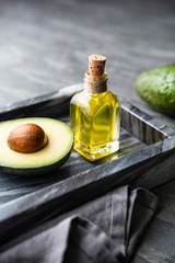 Healthy avocado oil in a glass bottle, decorated with sliced avocado