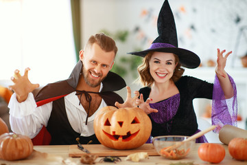 couple of people are preparing for Halloween in costumes of witch and vampire with pumpkins.