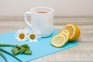 natural products for the treatment of seasonal colds, lemon, aloe, chamomile tea, blue background, wooden table, copy space