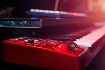 Electric Piano. Record sound, music. Making music, recording. Creating sound foundations. Red electric keyboard on the red background in the recording room.