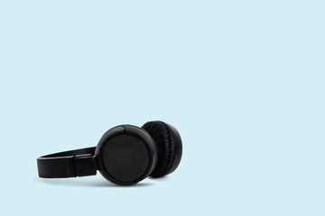 Black headphones on a pastel blue background. The concept of creating and listening to music. Comfortable headphones for listening to music. Creating sounds and listening to the foundations.