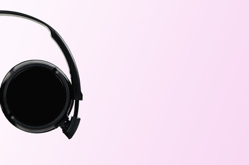 Black headphones on a pastel pink background. The concept of creating and listening to music. Comfortable headphones for listening to music. Creating sounds and listening to the foundations.