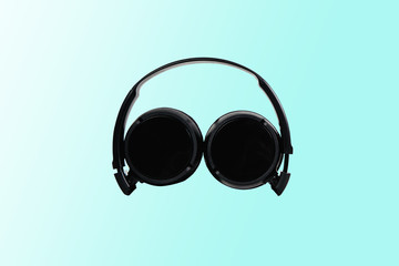 Black headphones on a pastel blue background. The concept of creating and listening to music. Comfortable headphones for listening to music. Creating sounds and listening to the foundations.