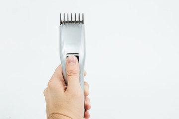 A hair clipper held in hand. The concept of cutting, improving the appearance. Going to the hairdresser, cutting hair at home. Taking care of appearance.