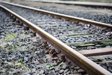 rusty metal railway tracks and brackets in a ballast bed, diagonal, selected focus, narrow depth of...